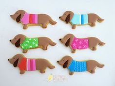 decorated cookies in the shape of dachshunds with different colored sweaters on them