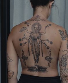 the back of a woman's body with tattoos on it