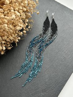 These very long black earrings made of sparkling beads with a blue gradient represent an elegant combination of style and sophistication. The black color gives the accessory a sense of severity, while the blue sparkling gradient adds brightness and striking contrast. Wear these earrings to create a refined and stylish look that will attract admiring glances. Made from Czech beads. Hypoallergenic clasp. Length 8 inches (20cm). Width 0.5 inches (1.5cm). If you want these earrings in a different color, write to me and I will be happy to make them for you. Fringe Bead Earrings, Extra Long Earrings, Ombre Earrings, Blue Gradient, Earrings Black, Earrings Long, Black Earrings, Seed Bead Earrings, Earrings Boho