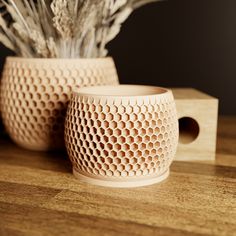 two vases sitting on top of a wooden table next to each other with dried plants in them