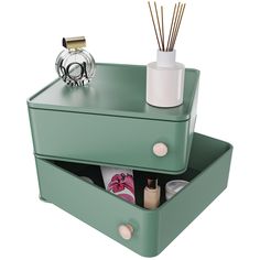 two green drawers with bottles and candles in them on top of each other next to a candle holder