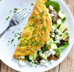 an omelet and salad on a white plate with a fork next to it