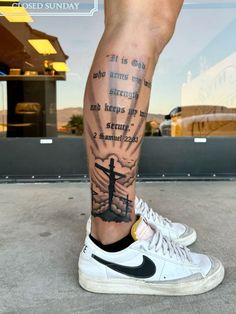 a man's leg with a cross and bible verse tattooed on the lower leg