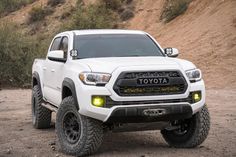 a white toyota truck parked on top of a dirt hill