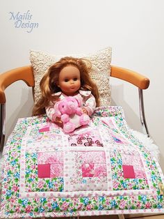 a doll sitting on top of a bed holding a pink teddy bear in it's lap