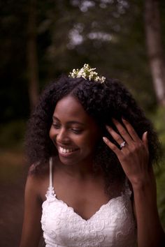 a woman in a wedding dress is smiling and holding her hair up to her face