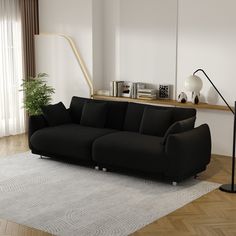 a black couch sitting on top of a white rug in a living room next to a window