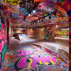 an indoor skate park with graffiti all over the walls