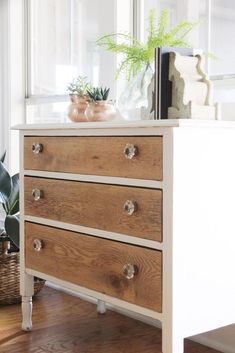 a white dresser with three drawers and a potted plant sitting on top of it