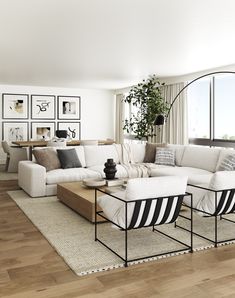 a living room filled with white furniture and lots of wood flooring next to a large window