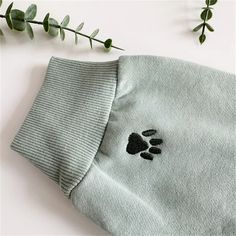 a t - shirt with a paw print on it next to a plant and leaves