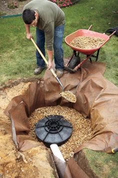 a man is shoveling gravel into a hole with a wheelbarrow in it