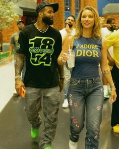 a man and woman are walking down the street with drinks in their hands while wearing matching outfits