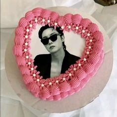 a heart shaped cake decorated with pink icing and white flowers, featuring an image of elvis presley