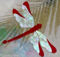 two red and white dragonflys sitting on top of a table next to each other