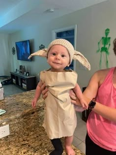 a woman holding a baby wearing a costume