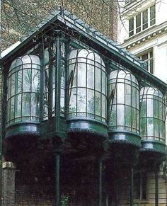 a green building with glass windows on the top floor and bottom part of it's roof