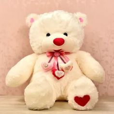 a white teddy bear sitting on top of a wooden floor next to a pink wall