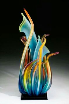 an artistic glass sculpture is displayed on a black stand