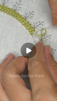 someone is working on a piece of fabric with yarn and scissors in their hands, while they are stitching it together