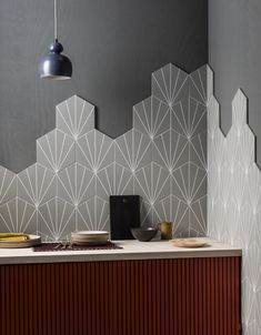 a kitchen counter with plates and bowls on it next to a wall that has geometric designs