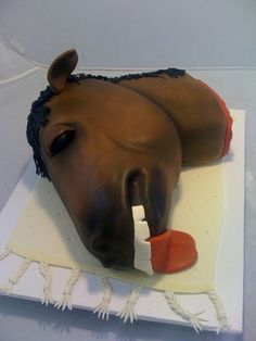 a cake shaped like a horse laying down on top of a white tablecloth covered table