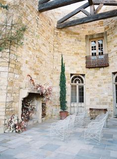 two white chairs sitting in front of a stone building