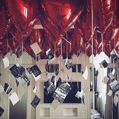 red balloons are hanging from the ceiling in front of a mirror with pictures on it