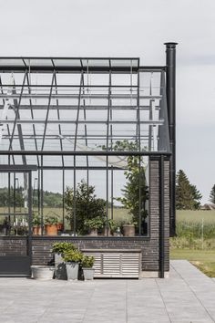 a glass building with potted plants in front of it and a bench on the outside