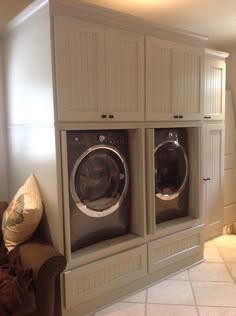 a washer and dryer sitting in front of a wall with built - in cabinets