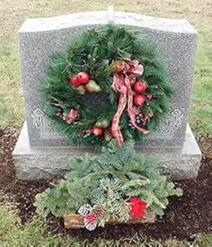 a wreath on top of a grave surrounded by greenery