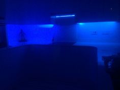 a dark room with blue lights on the ceiling and cabinets in the back ground,