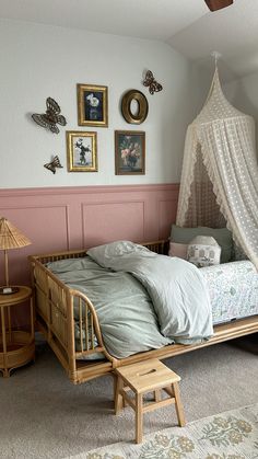 a bedroom with pink walls and white bedding in the corner, along with pictures on the wall