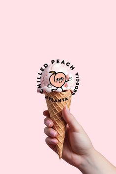 a hand holding an ice cream cone with a pink background