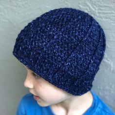 a young boy wearing a blue shirt and a crocheted beanie on his head