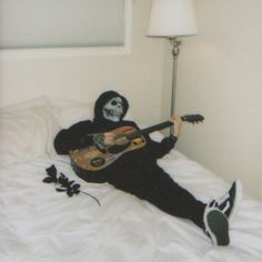 a person with a guitar laying on a bed