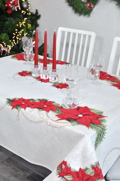 a christmas table setting with red candles and poinsettis on the table cloth