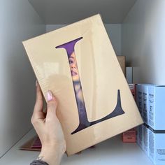 a person holding up a box with the letter l on it