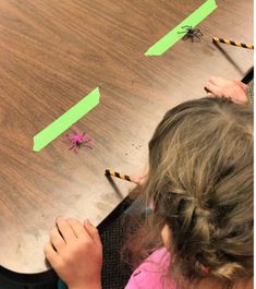 two children at a table playing with paper straws and spider puppets on the table