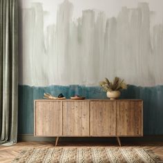 a wooden cabinet sitting in front of a wall painted with blue and white paint on it