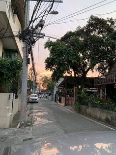 a car parked on the side of a road next to power lines and trees at sunset