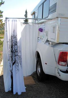 a white truck parked next to a tall curtain with trees on it's side