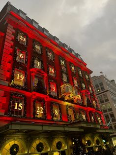 a large red building with clocks lit up on it's sides and windows at night