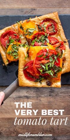 the very best tomato tart is cut in half and served on a cutting board