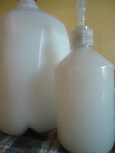 two plastic jugs sitting next to each other on top of a checkered table cloth