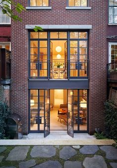 the entrance to an apartment building with glass doors and brick walls, surrounded by stone walkways