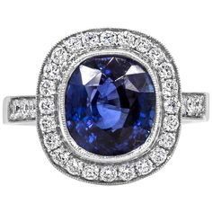 A vintage-style engagement ring, showcasing a bezel-set 4.12 carats cushion cut blue sapphire. Surrounded by a halo of round brilliant cut diamonds that continue on to the shank in a half-way setting. Accent diamonds weigh 0.56 carat total. Set on 18K white gold and finished with milgrain edges for an antique look. Size 6.5 US, resizable upon request.  Roman Malakov is a custom house, specializing in creating anything you can imagine. If you would like to receive a special quote on a custom piec Vintage Style Engagement Rings, Cushion Cut Engagement Ring, Diamond Halo Engagement Ring, Halo Diamond Engagement Ring, Diamond Halo, Halo Engagement Ring, Engagement Rings Sapphire, Brilliant Diamond, Halo Engagement