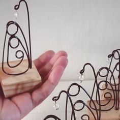 a hand holding a piece of wood with wire work on it and several smaller pieces in the background