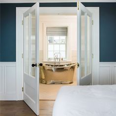 an open door leading to a bathtub in a bedroom