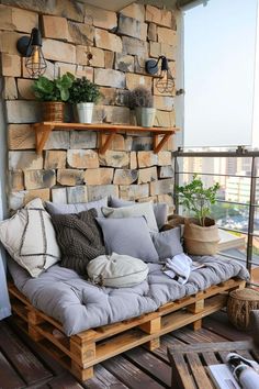 a couch made out of wooden pallets on top of a balcony with potted plants